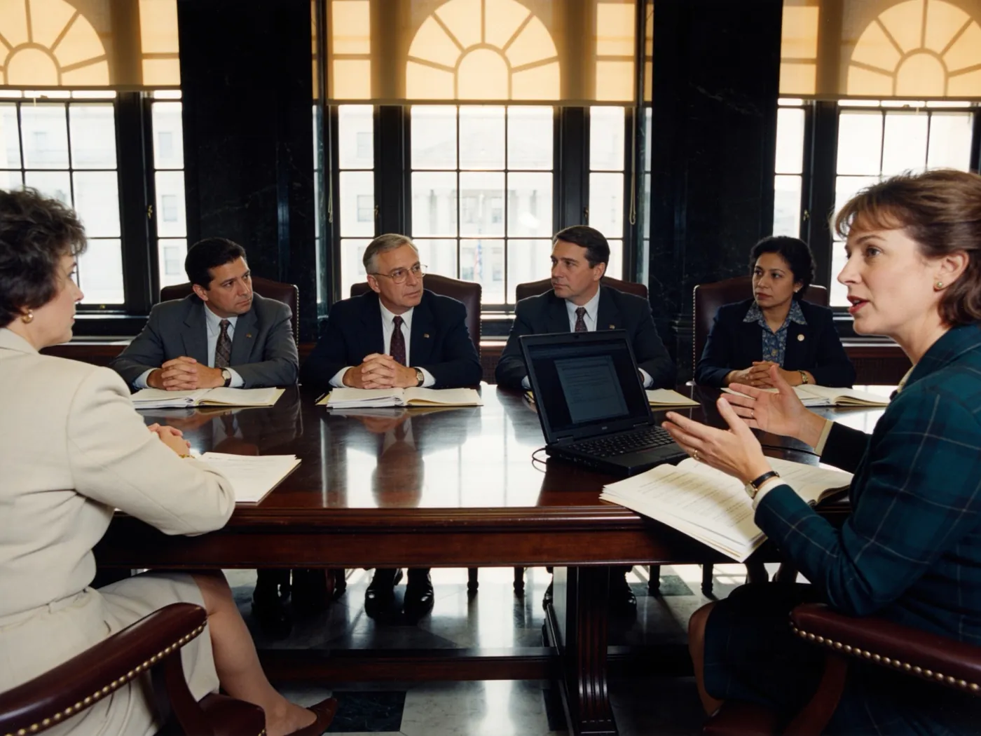 Education officials reviewing papers around a table in a government meeting room